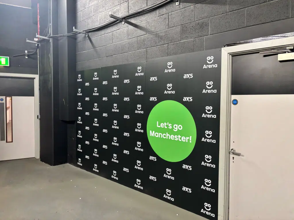 AO Arena branded step-and-repeat wall with 'Let's go Manchester' graphic