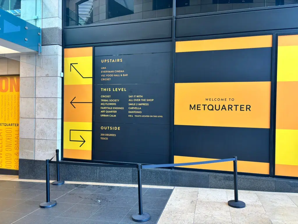 Metquarter Liverpool wayfinding and hoarding graphics in yellow and navy