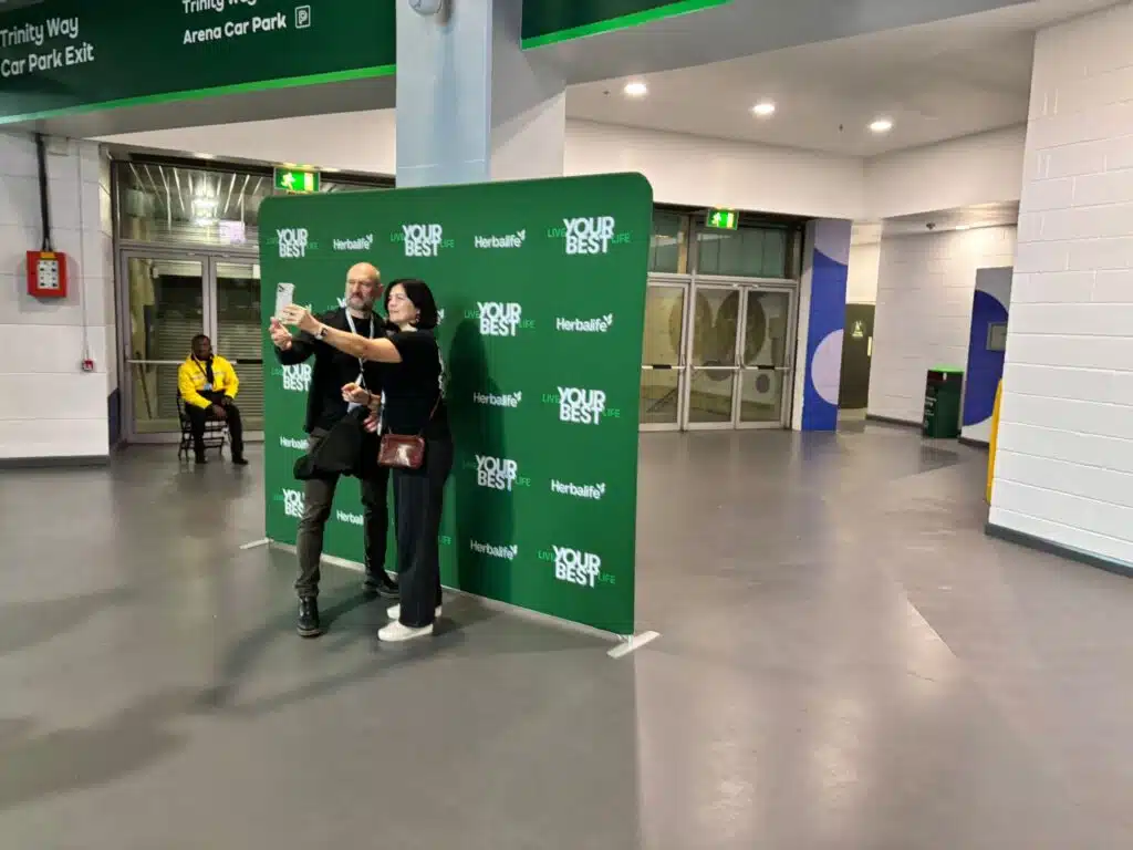 Visitors posing at a Herbalife branded photo wall