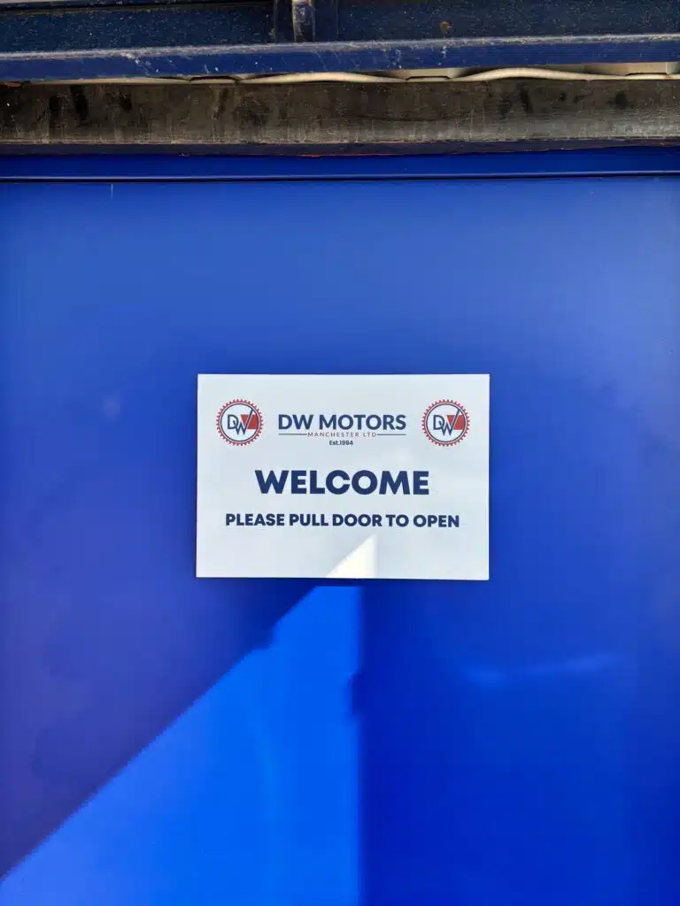 DW Motors welcome sign on a blue door
